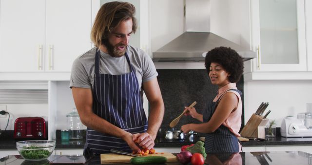 Couple preparing meal in modern kitchen, emphasizing teamwork and healthy eating lifestyle. Ideal for content focusing on cooking, domestic life, health, and relationships. Great for blogs, ads, and articles related to home cooking, recipe sharing, and kitchen appliances.