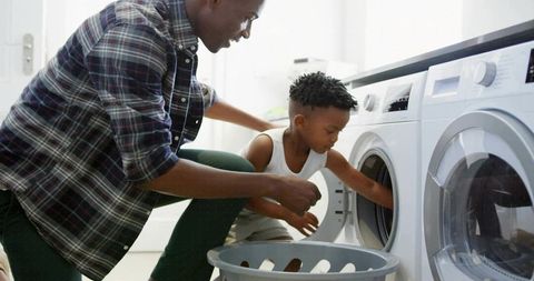 Parent and child loading washer together teaching laundry skills and home bonding