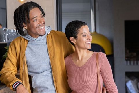 African american couple smiling and leaning at cafe counter, enjoying cozy coffee shop