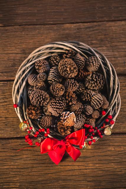 Grapevine wreath with red ribbon and pine cone on wooden table