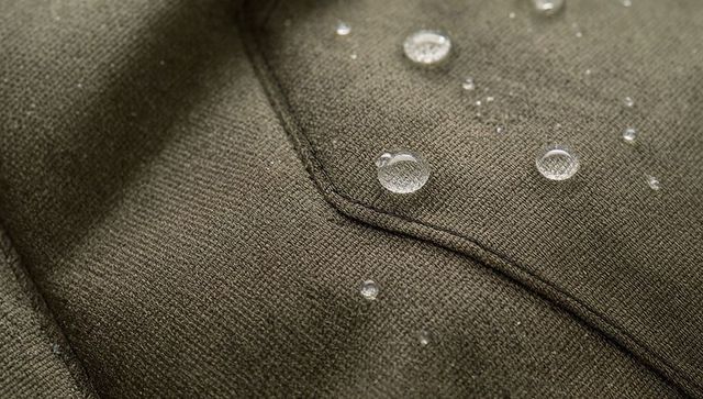 Olive green jacket fabric showing water beading on diagonal seamed piping macro texture