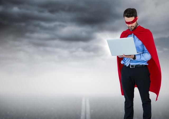 Businessman wearing red cape using laptop outdoors under cloudy sky, symbolizing confidence, power, and technological proficiency. Ideal for business concepts, technology solutions, marketing campaigns, digital transformation themes, leadership training materials, and motivational content.