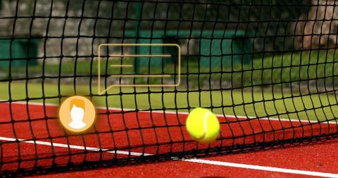 Tennis Ball Pressing Under Net on Vibrant Red Court