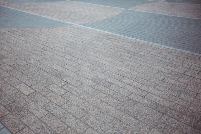 This image shows a two-tone brick pavement with a mix of light and dark bricks. The pattern creates a visually appealing texture, making it suitable for use in architectural designs, urban planning presentations, and construction project visuals. It can also be used as a background for websites, brochures, and advertisements related to outdoor spaces and landscaping.