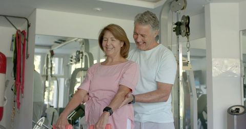 Senior Couple Exercising Together Lifting Dumbbells at Home