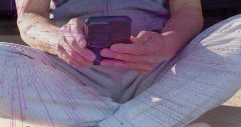 Closeup hands holding smartphone tapping screen crosslegged on sofa casual home use