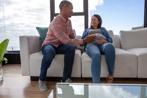 Expecting couple sharing tender moment on modern sofa