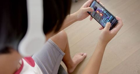 Asian Student Enthusiastically Engaging in Smartphone Gaming