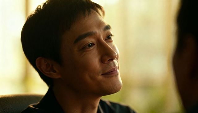 Warm headshot of smiling asian man in lounge with soft backlight and gentle expression