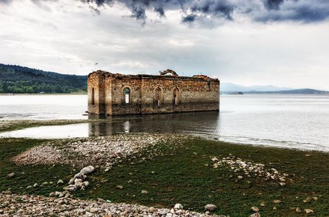 Ruins of historic church in drought-affected lakebed with dramatic sky