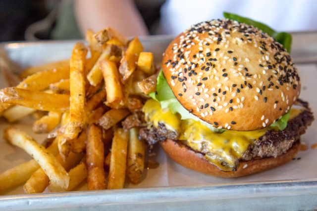 Mouth-watering cheeseburger with melted cheese and sesame seed bun accompanied by golden fries. Ideal for use in food blogs, restaurant menus, advertisements for fast food outlets, and articles on American cuisine or food photography.