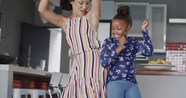 Happy diverse mother and daughter dancing at home. Lifestyle, family, togetherness and domestic life, unaltered.