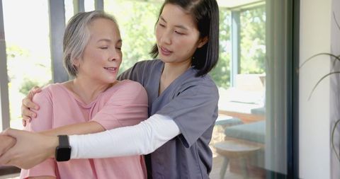Physical Therapist Assisting Senior Asian Woman with Arm Exercises