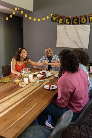 Diverse Group Laughing and Sharing Around Dining Table Celebration