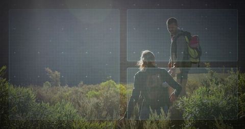 Hiker helping companion climb sunlit hillside with backpacks, teamwork and nature adventure