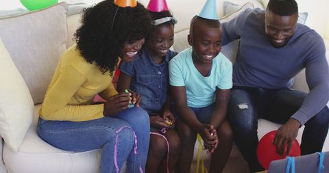 Family in party hats video chatting on laptop in living room