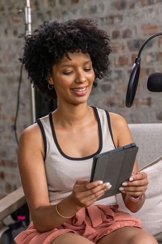 African american woman streaming and reading from tablet in brick studio