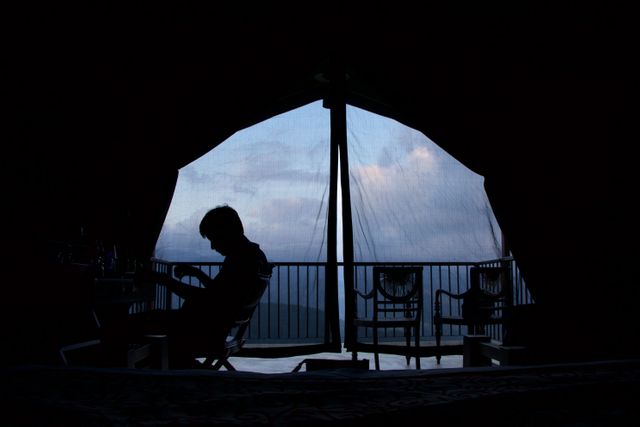 Silhouetted Person Relaxing on Balcony at Twilight - Download Free Stock Images Pikwizard.com