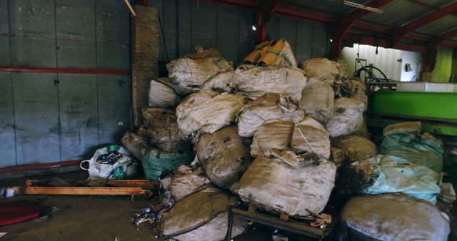 This image shows a sizeable stack of recyclable material bags inside an industrial warehouse setting. Ideal for illustrating waste management processes, recycling, and industrial applications. Can be used in articles or presentations about environmental sustainability, waste reduction efforts, or industrial operations.