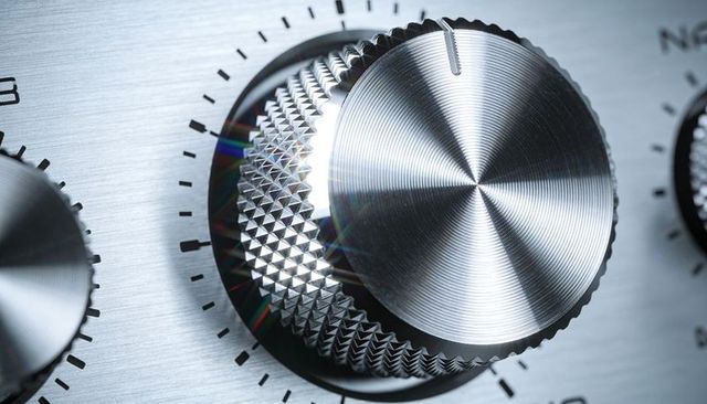 Macro close-up of brushed aluminum rotary knob on hi-fi amplifier with knurled grip