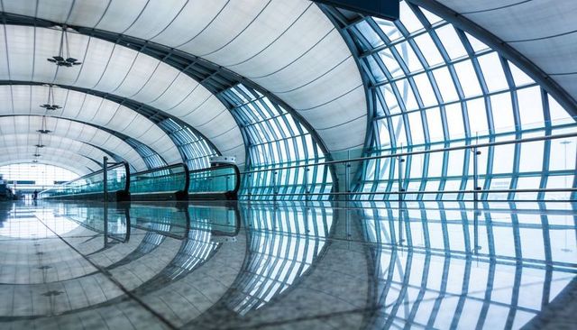 Futuristic airport concourse featuring curved glass arches and reflective marble floor