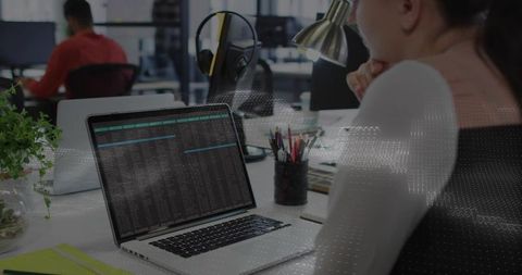 Woman studying laptop terminal in coworking office coding data with headphones