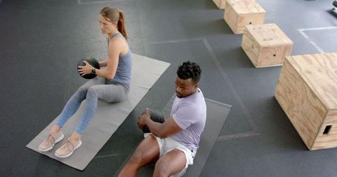 Diverse Athletes Strengthening Core with Medicine Balls at Gym