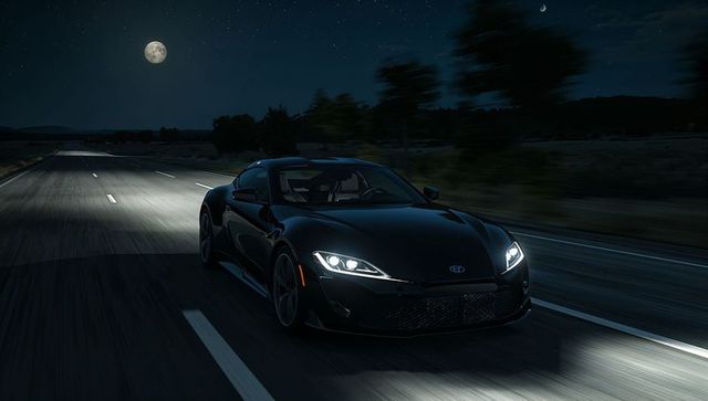 Black sports coupe racing on moonlit rural highway at night with led headlights
