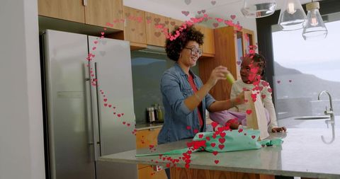Woman and child packing gift and sharing laughter in modern kitchen with water view