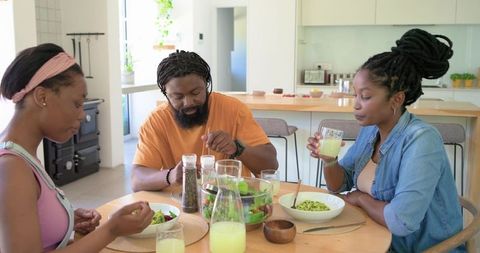African family sharing healthy lunch around modern kitchen table with salad and lemonade