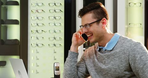 Smiling man talking on phone in modern optical store