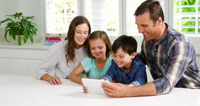 Happy Family Sitting at Kitchen Table Using Tablet Together - Download Free Stock Images Pikwizard.com