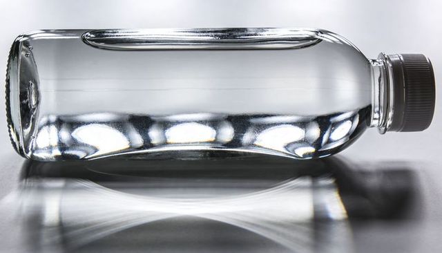 Clear Plastic Water Bottle Reflecting on Glossy Surface with Liquid Caustics and Shadow