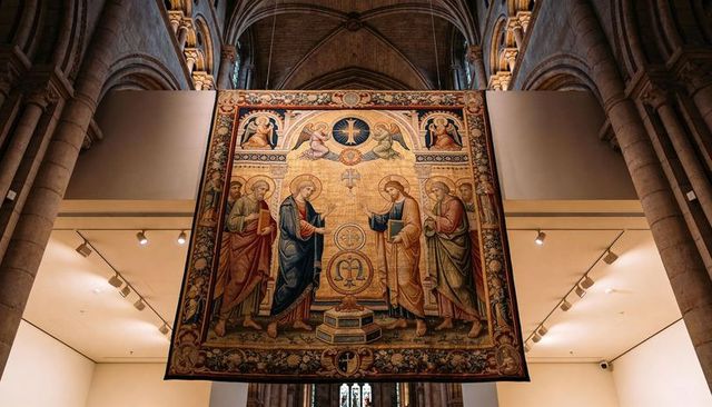 Gothic cathedral tapestry showing haloed saints and gold embroidered iconography