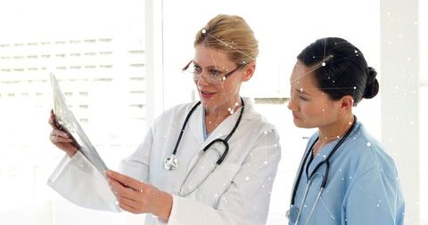 Female Doctors Reviewing X-Ray Together in Bright Clinic Collaborating on Patient Diagnosis