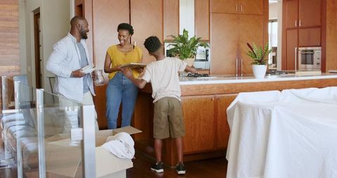 African American family unpacking in modern wooden kitchen, smiling and arranging plates