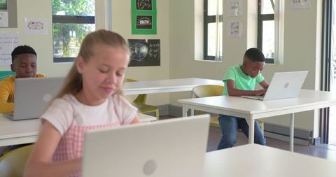 Multicultural Elementary Students Studying on Laptops in Bright Classroom