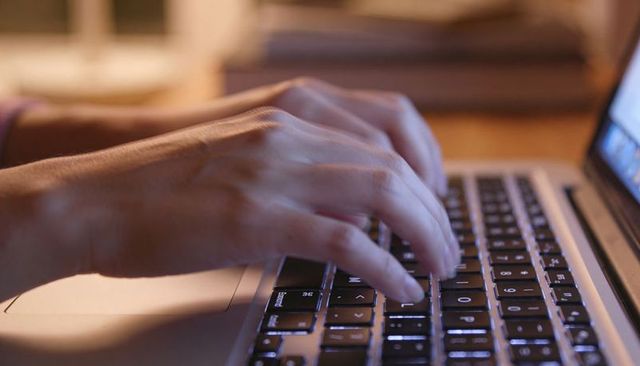 Typing Hands on Backlit Laptop Keyboard in Cozy Home Workspace for Remote Work