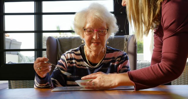 Senior Woman Eating with Caregiver Assistance at Home - Download Free Stock Images Pikwizard.com