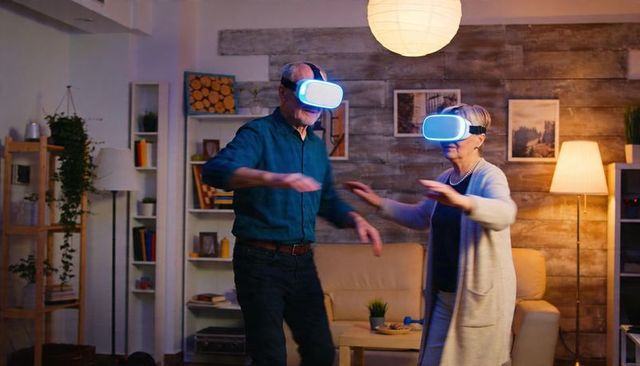 Senior couple experiencing virtual reality at home with blue-glow headsets and gesturing