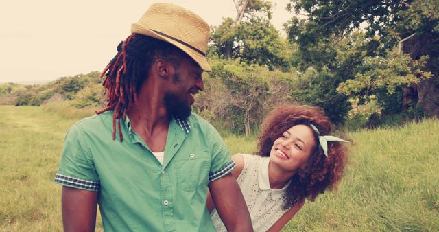A young African American couple is enjoying a romantic moment outdoors, with copy space. Their affectionate gaze and smiles suggest a deep connection and happiness in each other's company.