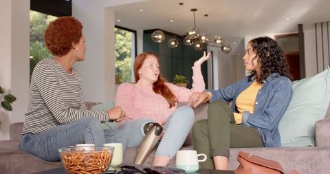 Diverse Women Sharing Snacks and Relaxing in Bright Modern Living Room