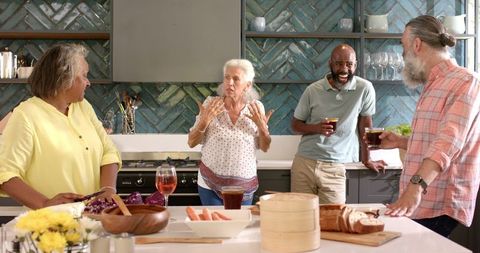 Senior Friends Cooking and Enjoying Drinks in Modern Kitchen