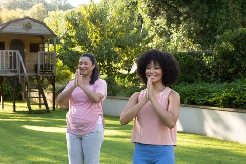 Mother and daughter practicing yoga pose outdoors in tranquil garden