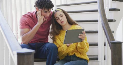 Young Biracial Couple Using Tablet on Stairs at Home