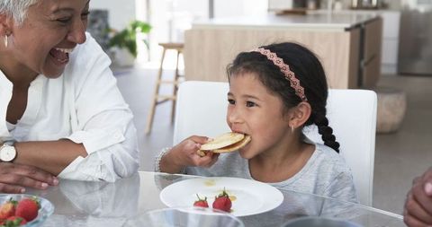 Grandmother and Granddaughter Enjoying Breakfast Together in Bright Kitchen