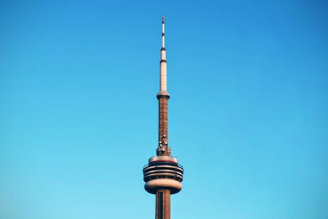 Featuring the iconic CN Tower set against a clear blue sky, this image captures the modern architectural marvel in Toronto, Canada. Ideal for travel blogs, tourism marketing, website headers, and educational materials concerning famous landmarks and Canadian architecture.