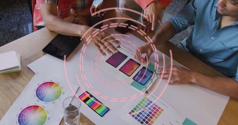 Creative Team Discussing Color Palettes Over Futuristic Digital Interface