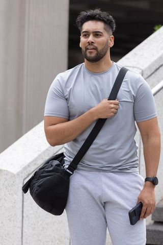 Urban commuter carrying duffel bag on shoulder walking concrete steps wearing smartwatch