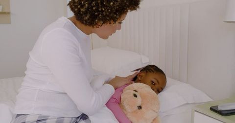 Mother Comforting Daughter at Bedtime Holding Teddy Bear
